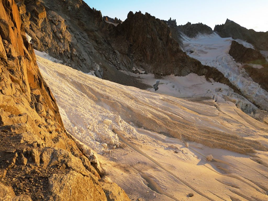Vypadnuté snehové a skalné lavíny ležia na ľadovci ako dračie chrbty